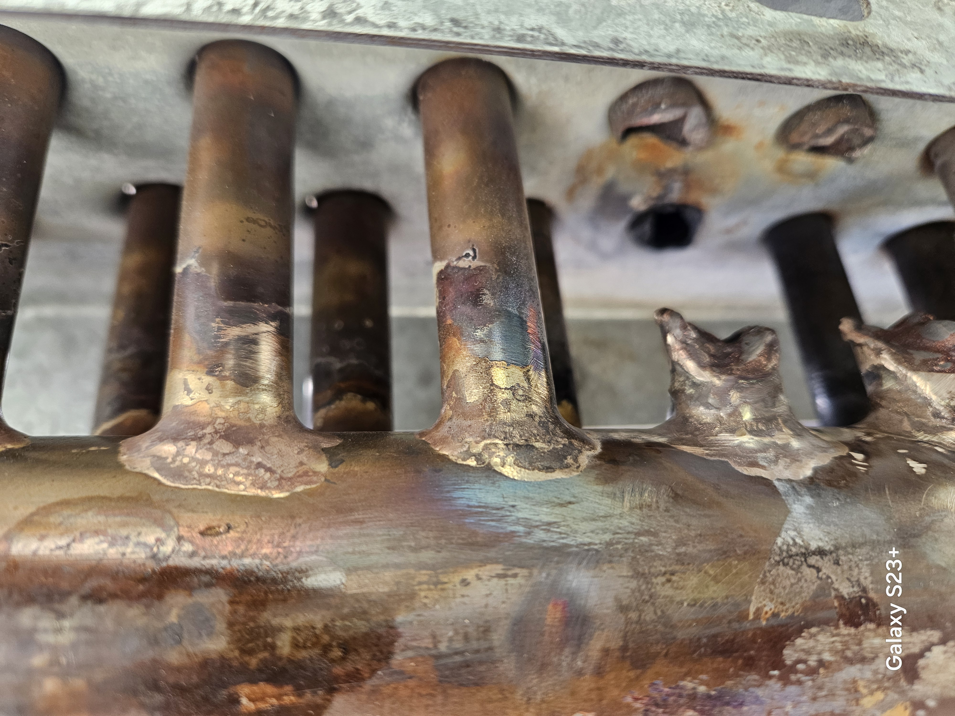 Close inspection of damaged industrial coil tube and header connections